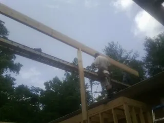 Carpenter setting a ridge beam over a new addition frame — Ice Dam Removal by Roofing Brothers in Saint Michael