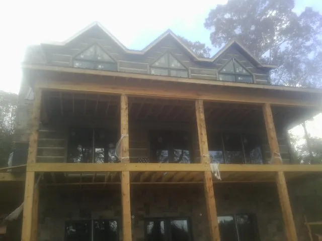 Dormers and porch framing on a large log home under construction — Roof Coating work by our crew in Saint Michael