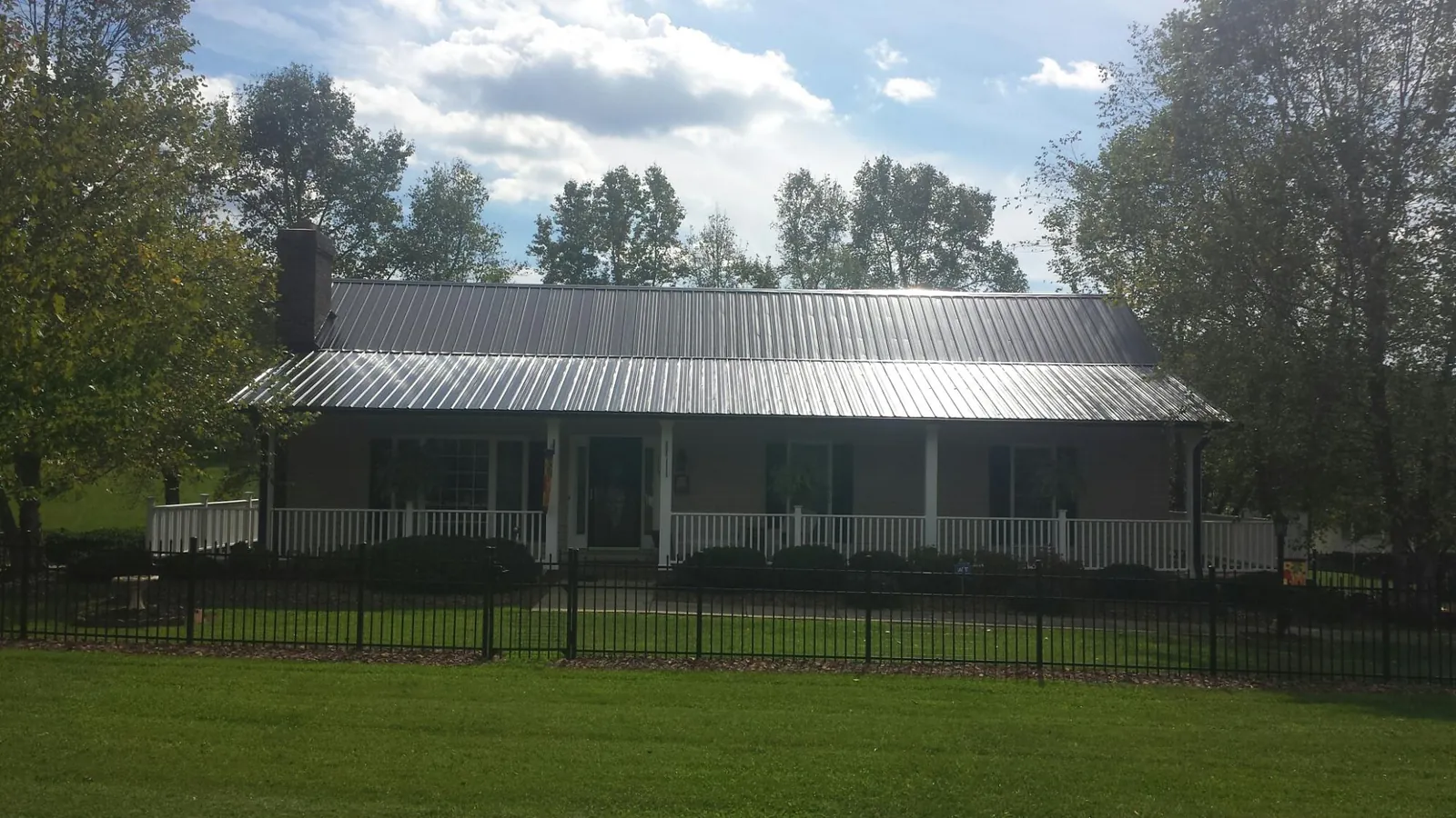 Gray metal roof on a brick ranch with a full width front porch — Gutter Guard Installation work by our crew in Saint Michael