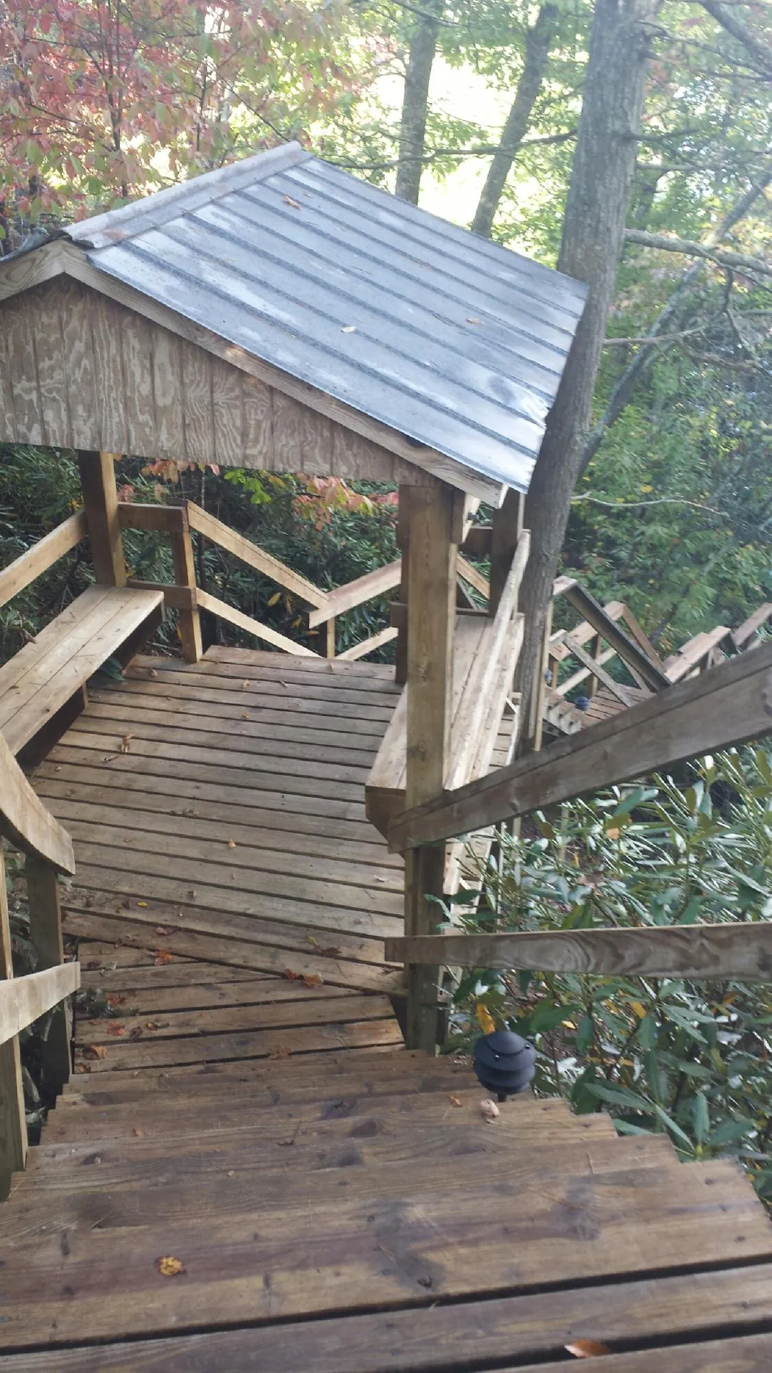 Metal roofed shelter over wooden steps on a wooded walkway — Skylight Repair & Installation work by our crew in Saint Michael