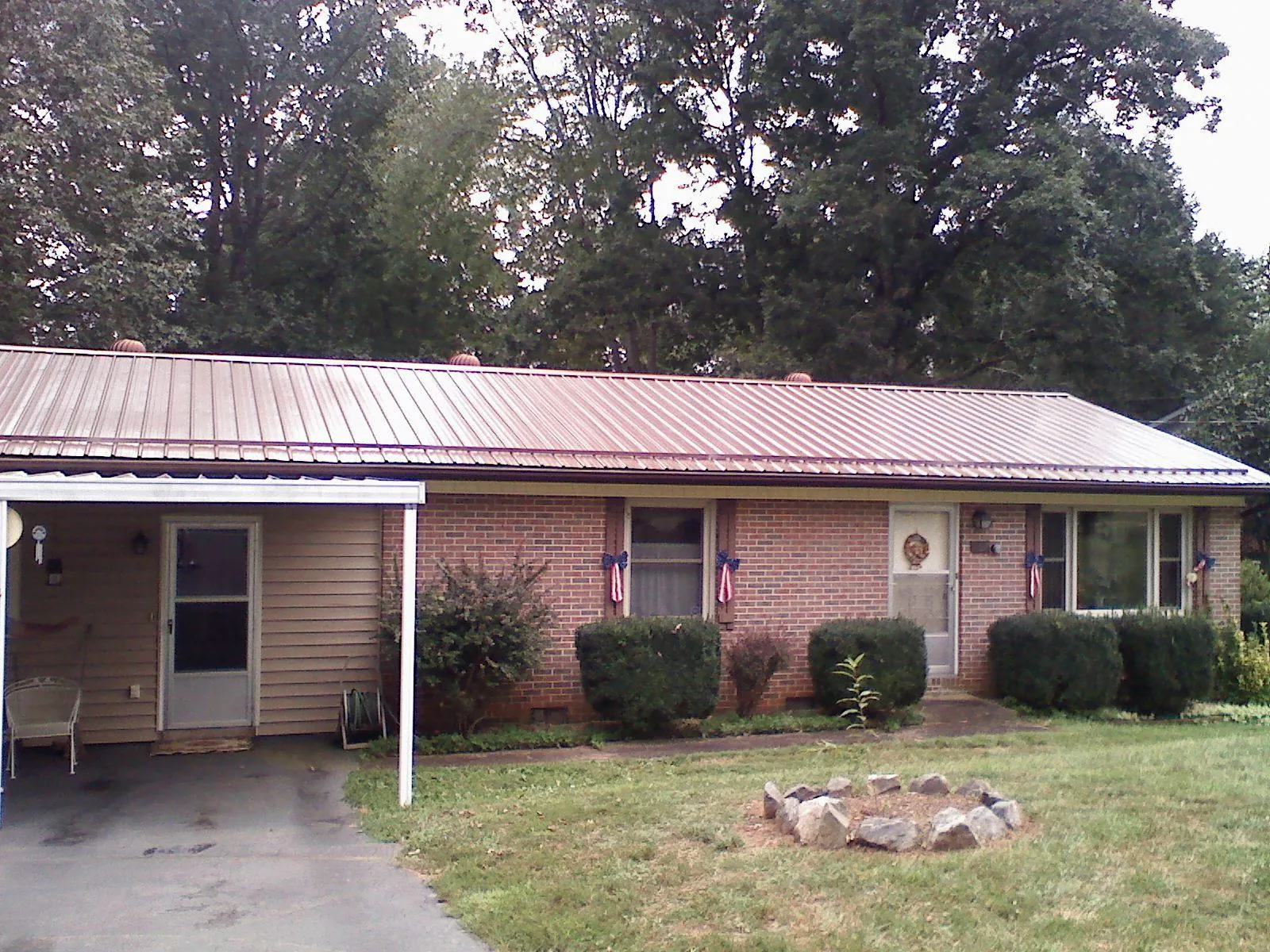 Bronze metal roof and carport on a brick ranch home — Roof Repair work by our crew in Saint Michael
